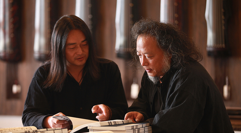 主编王鹏先生与执行主编陈逸墨先生在欣赏新出版的《自远堂琴谱》
